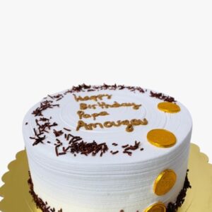 White birthday cake with whipped cream sprinkled with chocolate shavings and gold discs